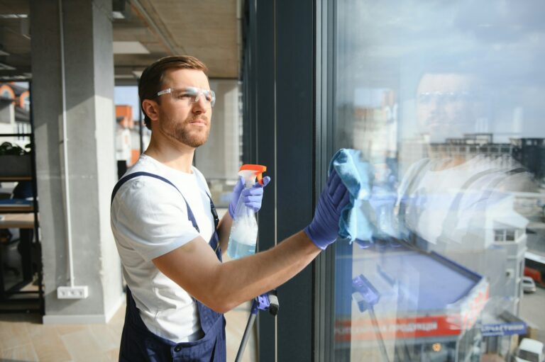 An employee of a professional cleaning service washes the glass of the windows of the building.